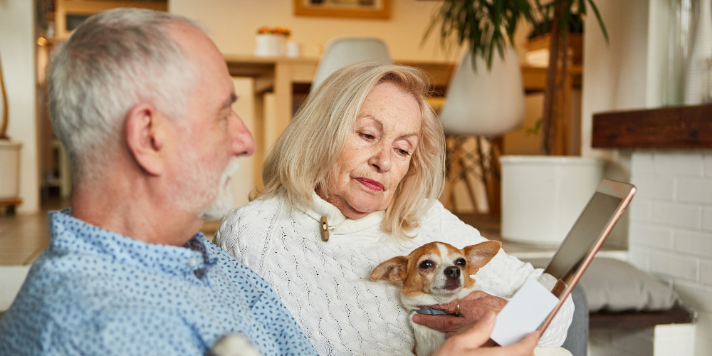 image of a retired couple with their dog using a tablet computer
