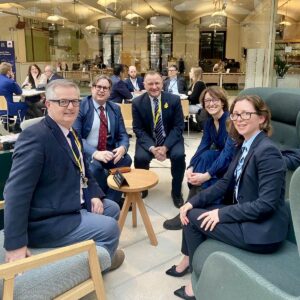 Drew Hendry MP and Brendan O’Hara MP meeting in Parliament with Julian Francis Godolphin, Elanor Warburton, and Rebecca Barnett from Ofgem. They are all sitting on chairs, smiling at the camera.